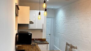 A compact kitchen with a wooden table, two bar stools, and pendant lighting. - Spacious 3 Bed Flat in Greenwich for 6 (London)