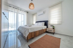 Een moderne slaapkamer met een bed, nachtkastjes, een hanglamp en uitzicht op de omgeving.