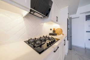 A modern kitchen with a gas stove, white herringbone backsplash, and stainless steel appliances.