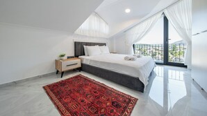 Un dormitorio con cama, mesita de noche y vistas de la ciudad desde un balcón.