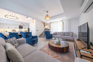 A modern living room with a sofa, armchairs, a coffee table, and a television.