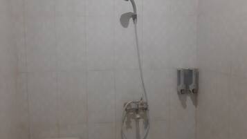 Een badkamer met een douche, toilet en een muurkraan.