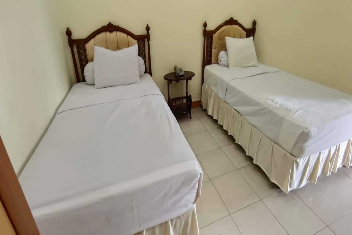 Two single beds with wooden headboards, white bedding, and a small bedside table with a telephone.
