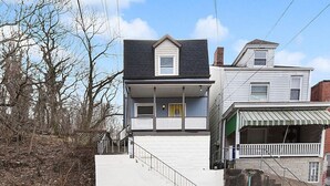 A two-story house with a front porch and a staircase leading to the entrance.
