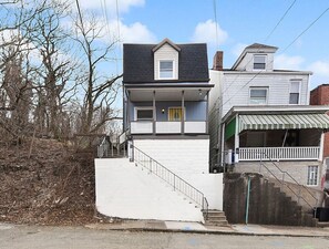 A two-story house with a front porch and a staircase leading to the entrance.