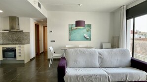 Uma sala de estar moderna com sofá, mesa de jantar e área de cozinha.