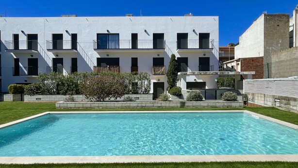 Um edifício moderno com piscina em frente.