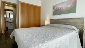 Una camera da letto con un letto, un armadio in legno, un bagno con un lavandino e un quadro appeso al muro.