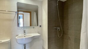 A bathroom with a sink, mirror, and shower.