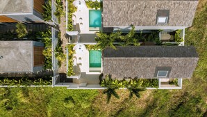 Un resort moderno con varias piscinas, mobiliario exterior y abundante vegetación.