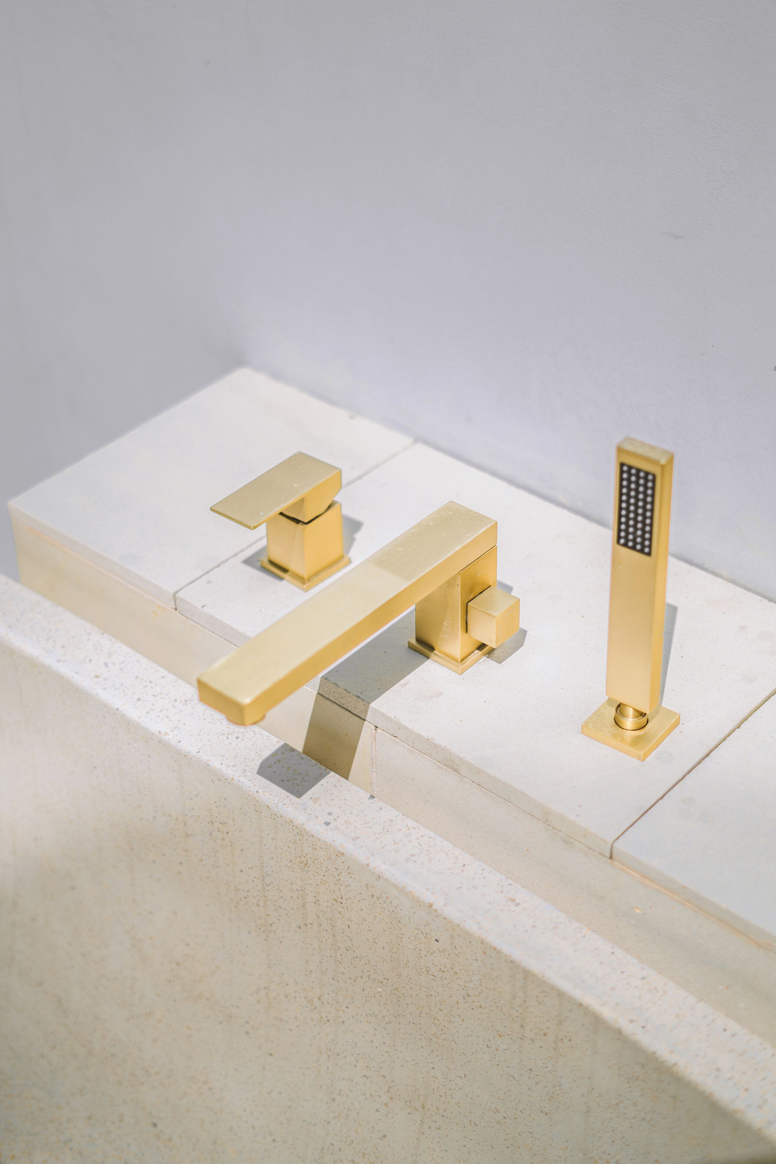 Une maquette d’une salle de bain avec un plan de toilette blanc, un robinet doré et une pomme de douche dorée.