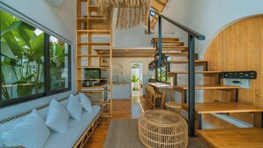 Un interior moderno con una escalera de madera, una zona de comedor y un espacio de estar con sofá y cojines.