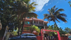 A hotel with a red entrance gate, palm trees, and a clear blue sky.