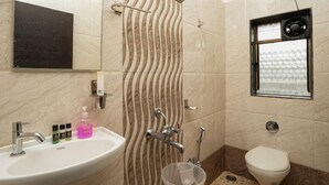 A bathroom with a sink, mirror, shower, toilet, and a window with a patterned view.