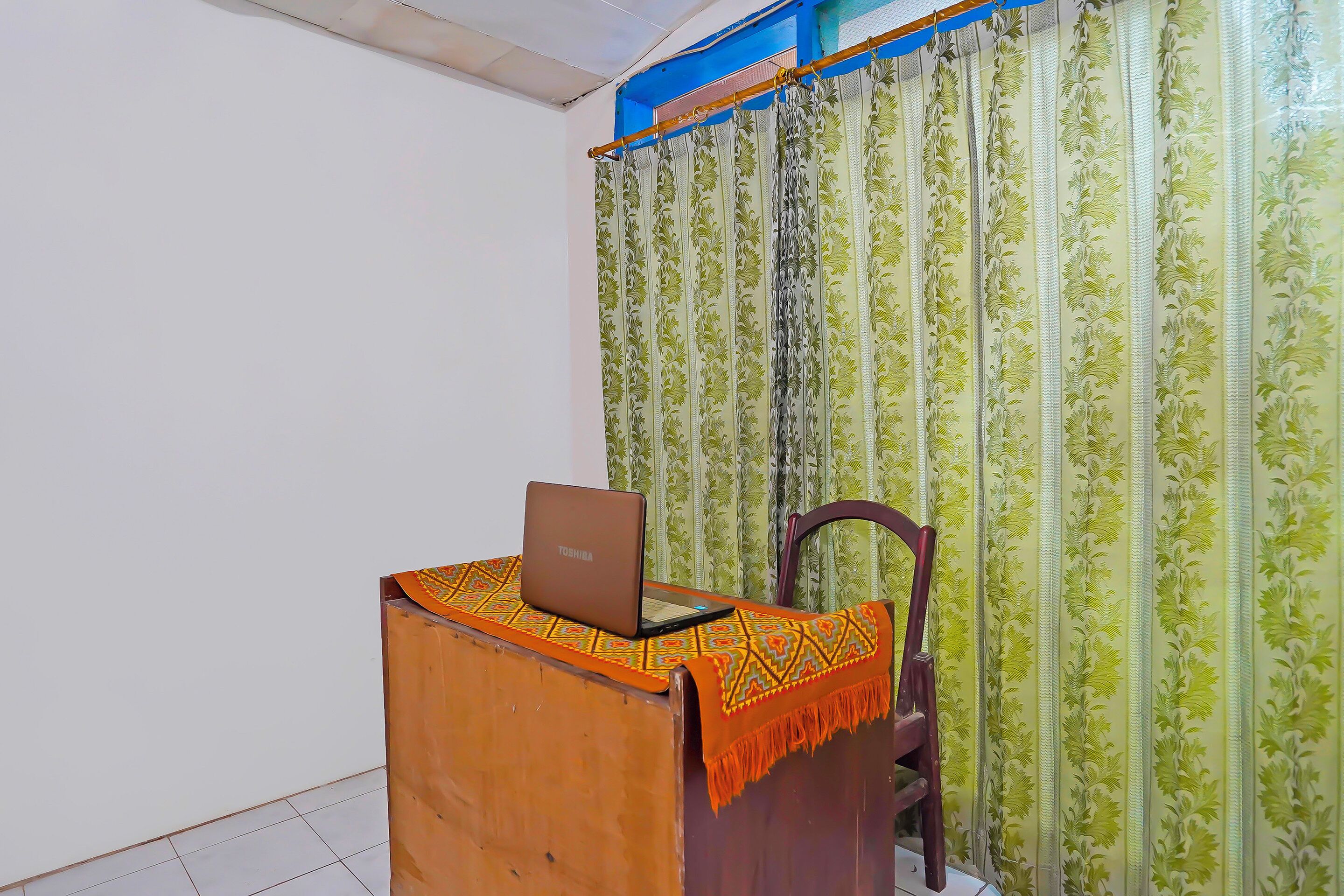 A room with a wooden desk, a laptop, and a chair.