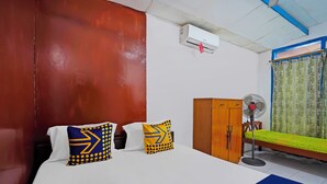A room with a bed, two pillows, a wooden wardrobe, a standing fan, and a window with curtains. - OYO Life 92651 Meir E-homestay Syariah (Surabaya)