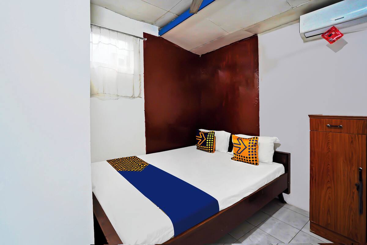A bedroom with a bed, wooden headboard, and a wardrobe.