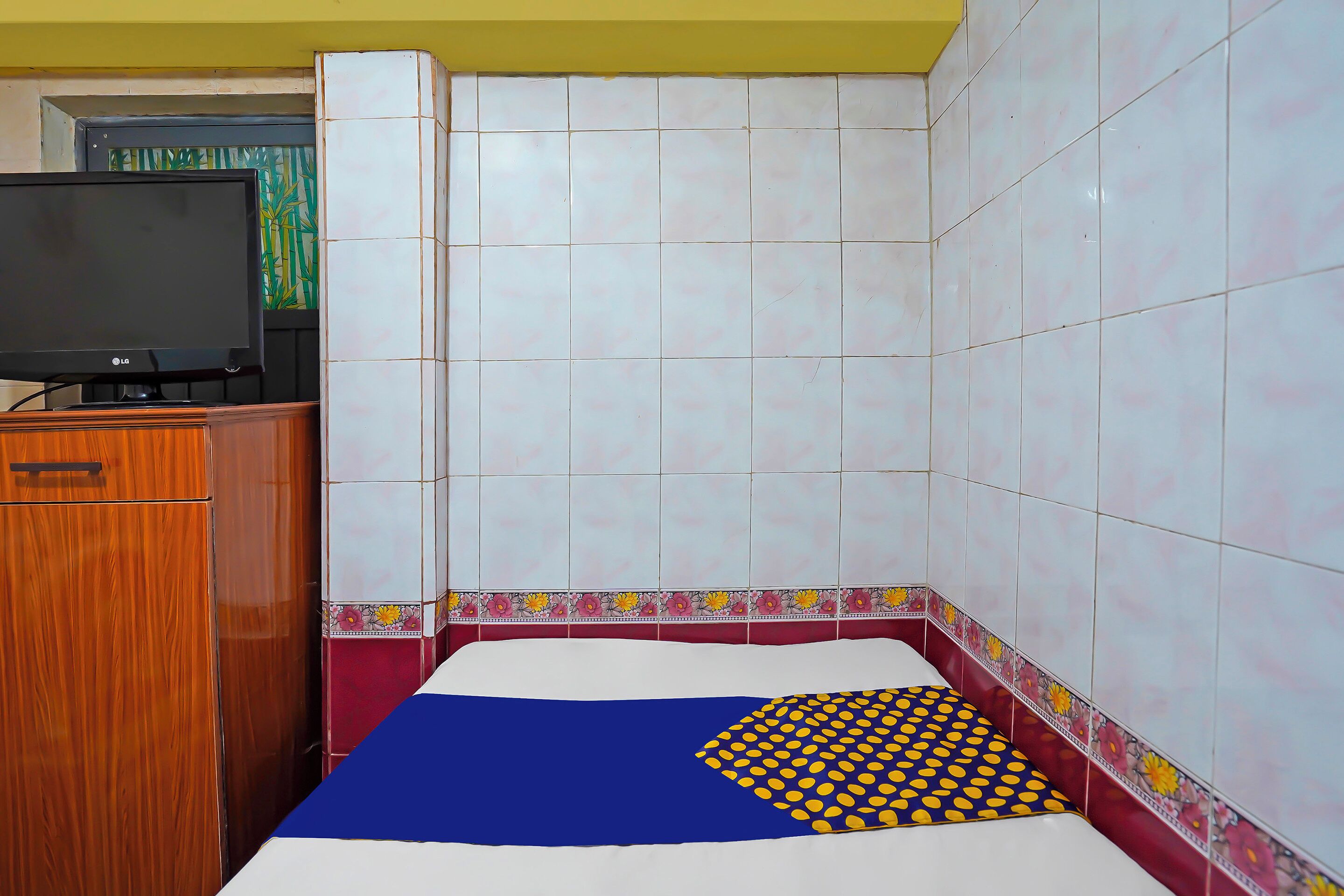 A small room with a bed, a wooden cabinet, and a television.