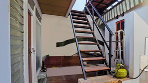 A staircase with a metal handrail leading to a landing. A green gas cylinder is placed on the landing. - OYO Life 92651 Meir E-homestay Syariah (Surabaya)