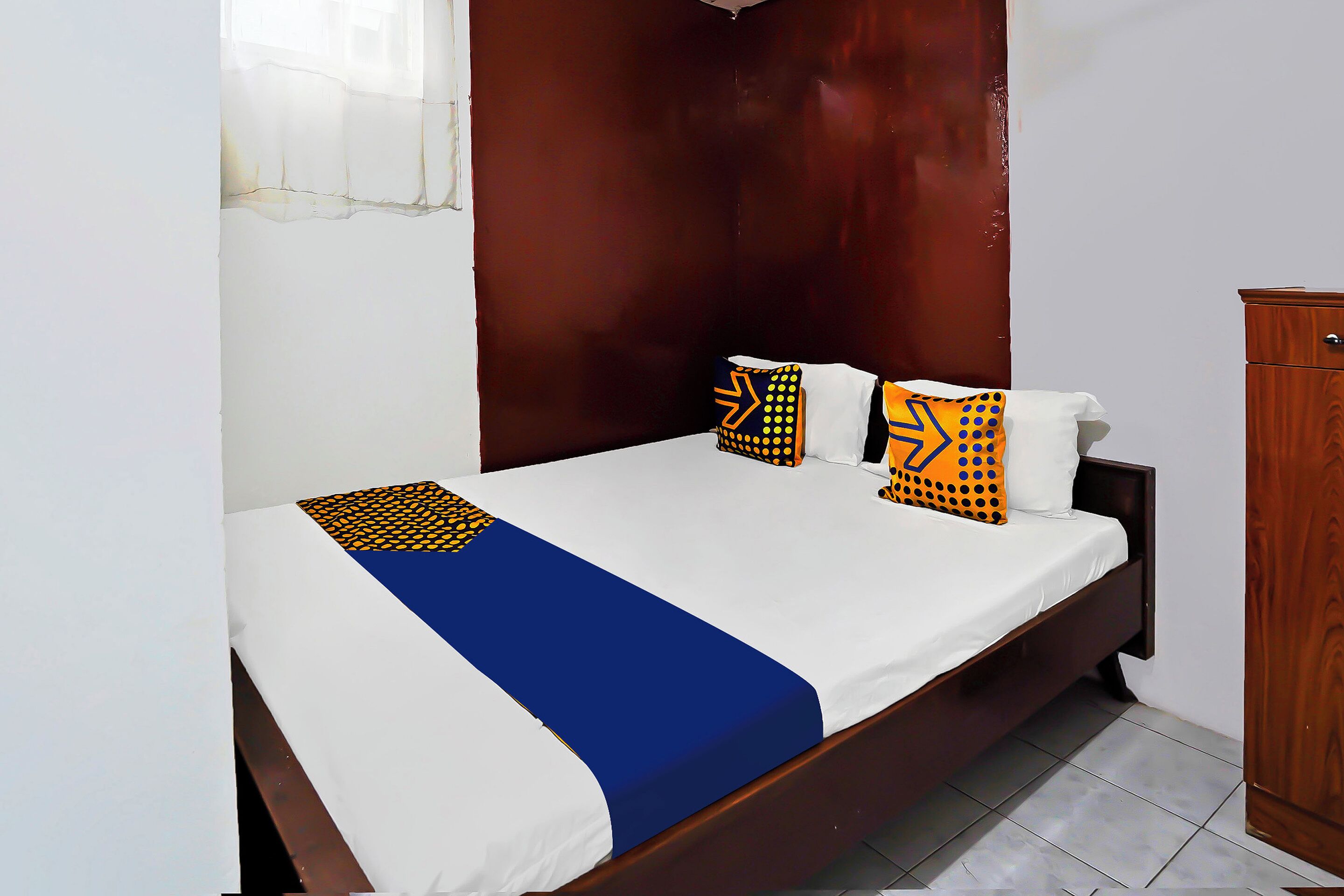 A bed with a blue and white bedspread, two pillows with geometric patterns, and a wooden headboard.