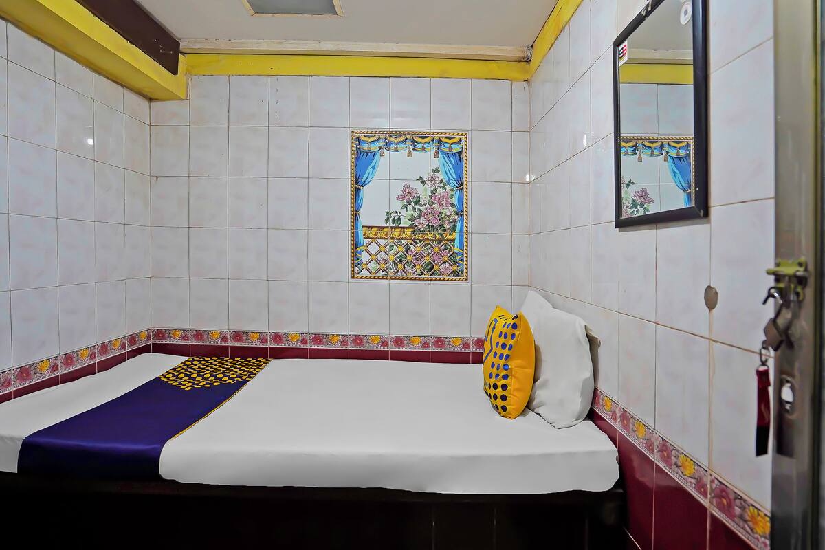 A hotel room with a bed, a window with a floral design, and a mirror on the wall.