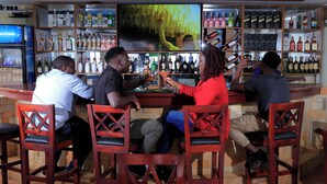 Un bar con diversas opciones de asientos y una gran variedad de botellas en estanterías.