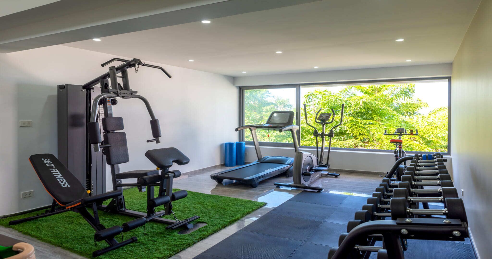Ein modernes Fitnessstudio mit Laufband, Crosstrainer und Gewichtbank.