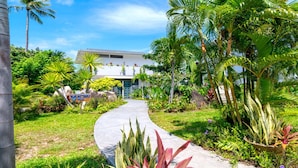 Un camino que lleva a una villa rodeada de exuberante vegetación tropical y palmeras.