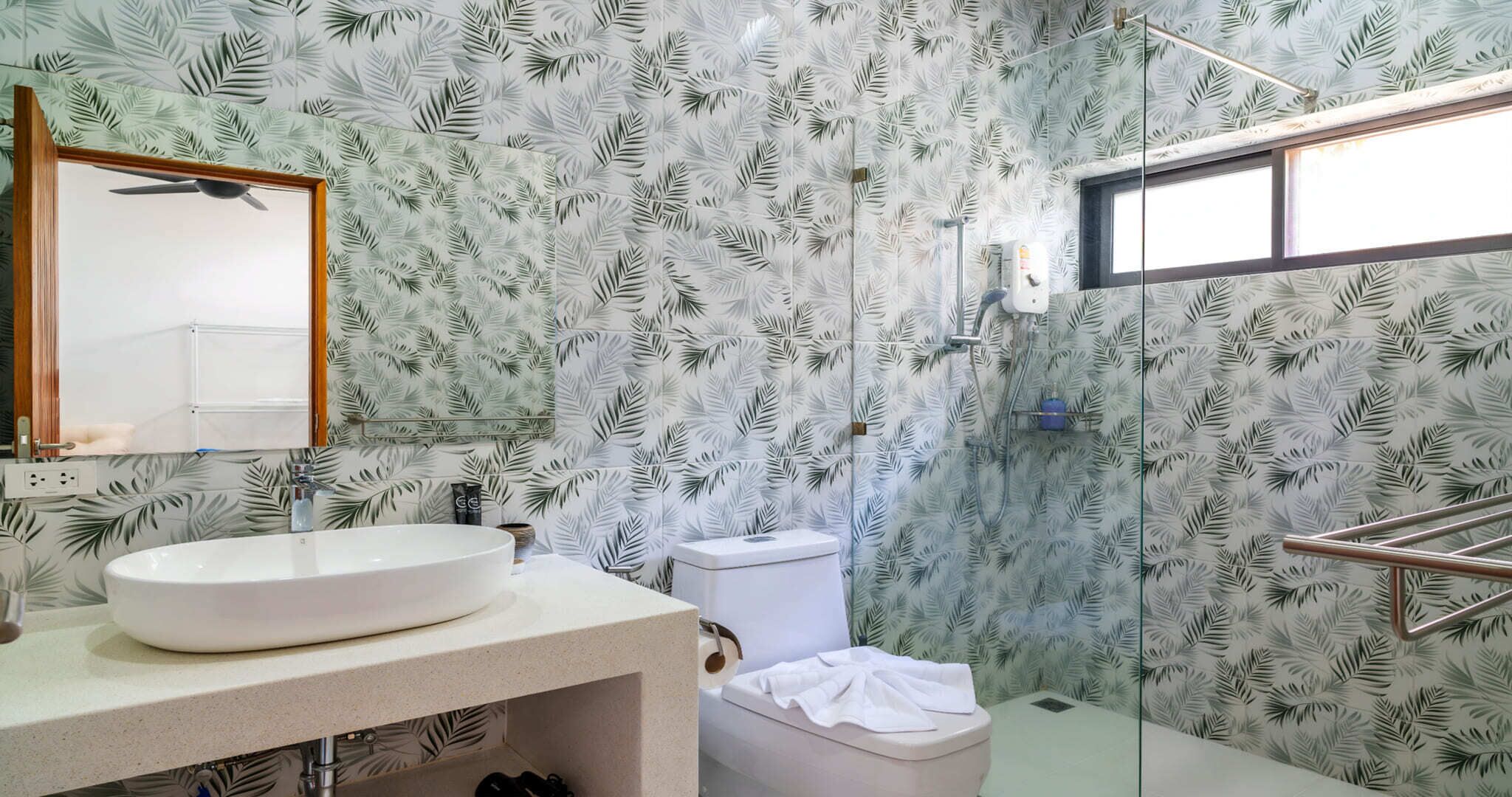 A bathroom with a large white sink, a toilet, and a shower area.