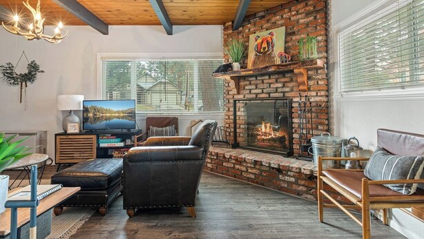 Una sala de estar con chimenea, sofá de cuero, televisor y estantería.