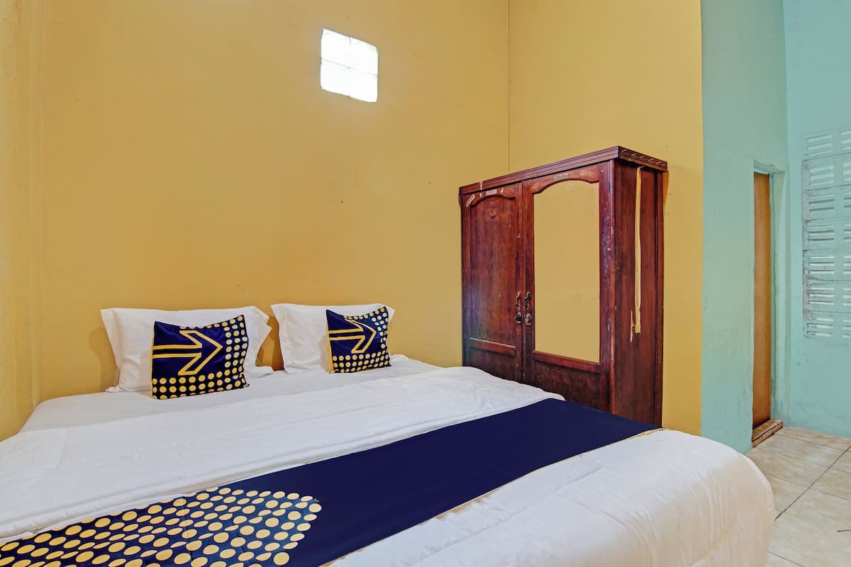 Un dormitorio con cama, dos almohadas, un armario de madera y una ventana.