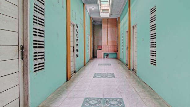 A narrow hallway with a tiled floor and doors on both sides. - Hotel O Penginapan Syafira Near Perumahan Mustamindo Permai 1 (Pekanbaru)