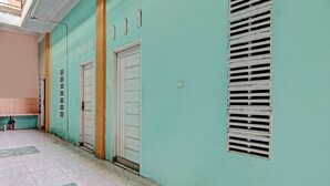 A hallway with two doors, a vent, and patterned floor tiles. - Hotel O Penginapan Syafira Near Perumahan Mustamindo Permai 1 (Pekanbaru)
