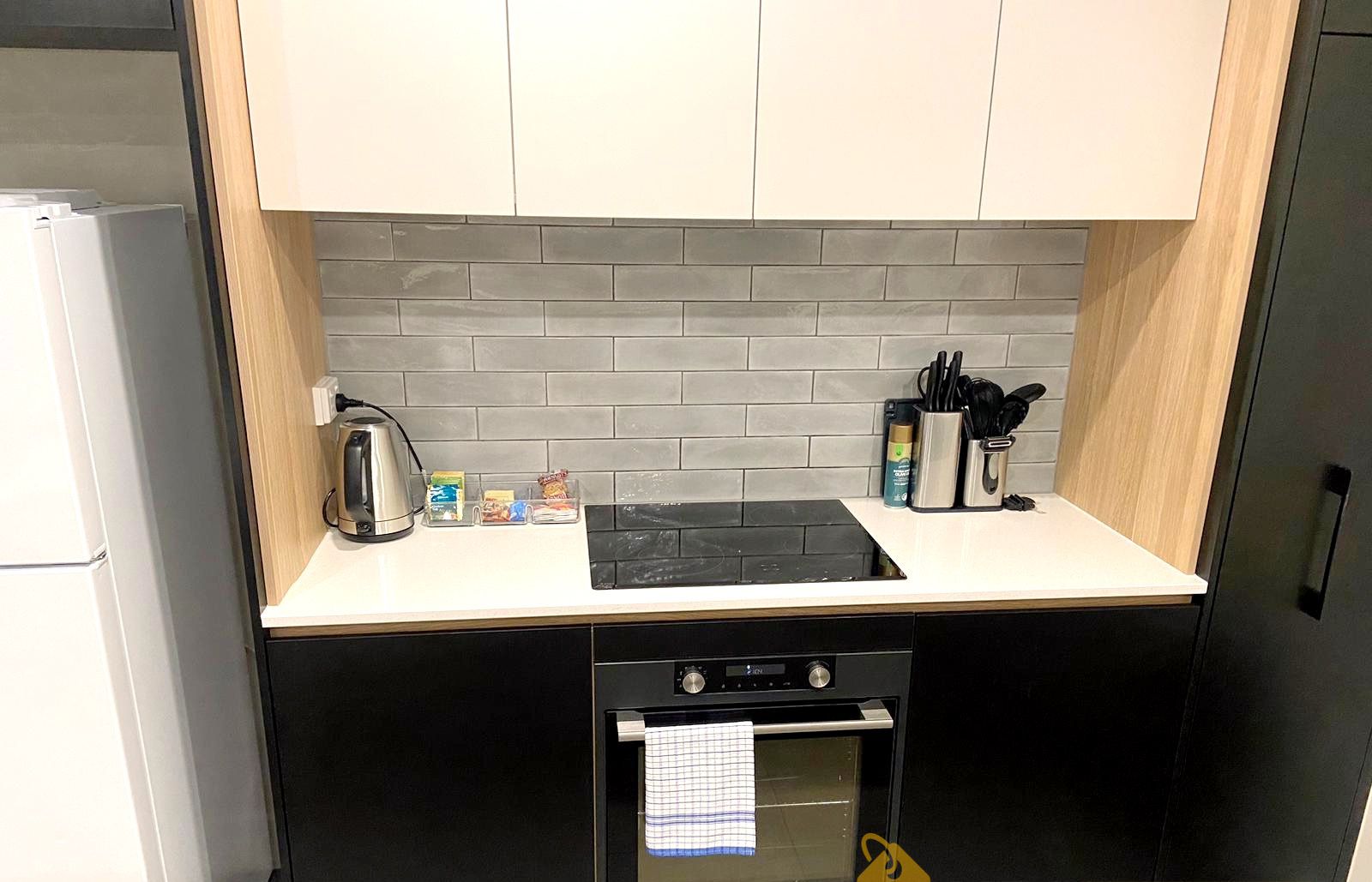 A compact kitchen with a black oven, a built-in stovetop, and a white countertop.