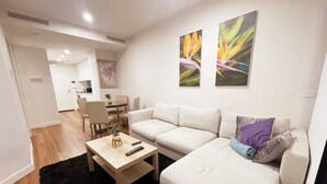 Un salon moderne avec un canapé, une table basse et, au fond, un coin repas.