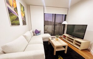 Un salon moderne avec un canapé, une table basse, un téléviseur et un balcon offrant une vue agréable.