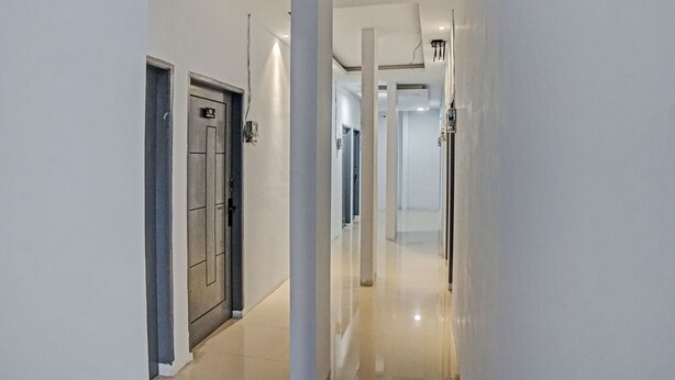 Un couloir moderne et bien éclairé, doté d’un plancher ciré, qui mène à une porte sur laquelle est apposée une enseigne.