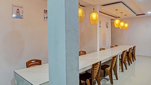Une salle de conférence avec une longue table, des chaises et des lampes suspendues.