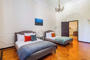 A hotel room with two beds, a chandelier, a painting, and a wooden floor. - Estoril Royal Atlantic Villa (Cascais)