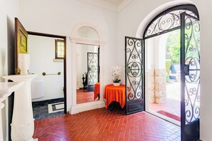 A hotel entrance with a red tiled floor, a white pillar, a mirror, and a table with a red tablecloth. - Estoril Royal Atlantic Villa (Cascais)