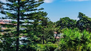 A swimming pool surrounded by lush greenery, a wooden deck with outdoor furniture, and a clear blue sky. - Estoril Royal Atlantic Villa (Cascais)