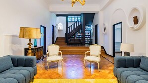 A spacious living area with a wooden staircase, two armchairs, a sofa, and a chandelier. - Estoril Royal Atlantic Villa (Cascais)