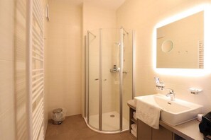 Une salle de bain avec une douche à parois de verre, un lavabo avec un miroir et un porte-serviettes.