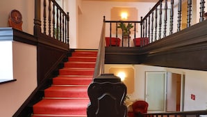 Una escalera con peldaños cubiertos de alfombra roja y barandillas negras.
