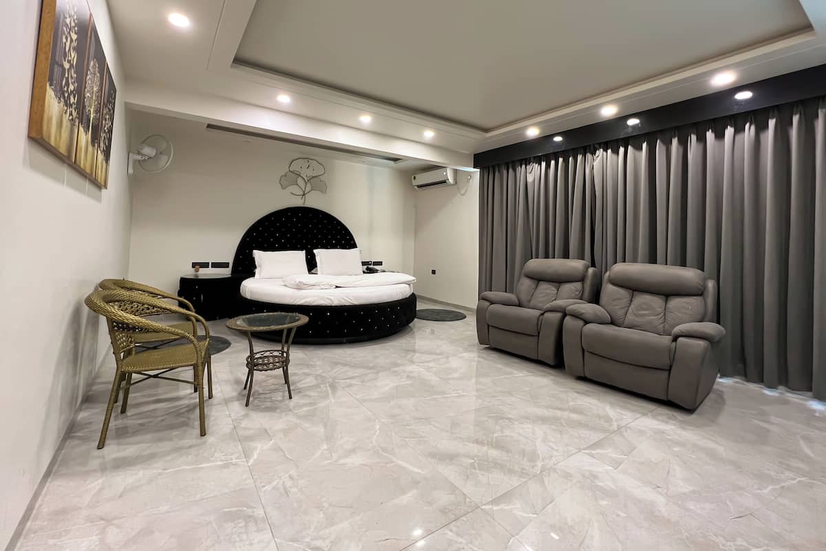 Un dormitorio moderno con una cama grande, un espacio de descanso con dos sillas y una mesita.