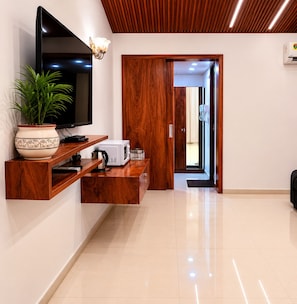Sala de estar moderna com televisão de tela plana, estantes de madeira, um vaso de planta e micro-ondas.