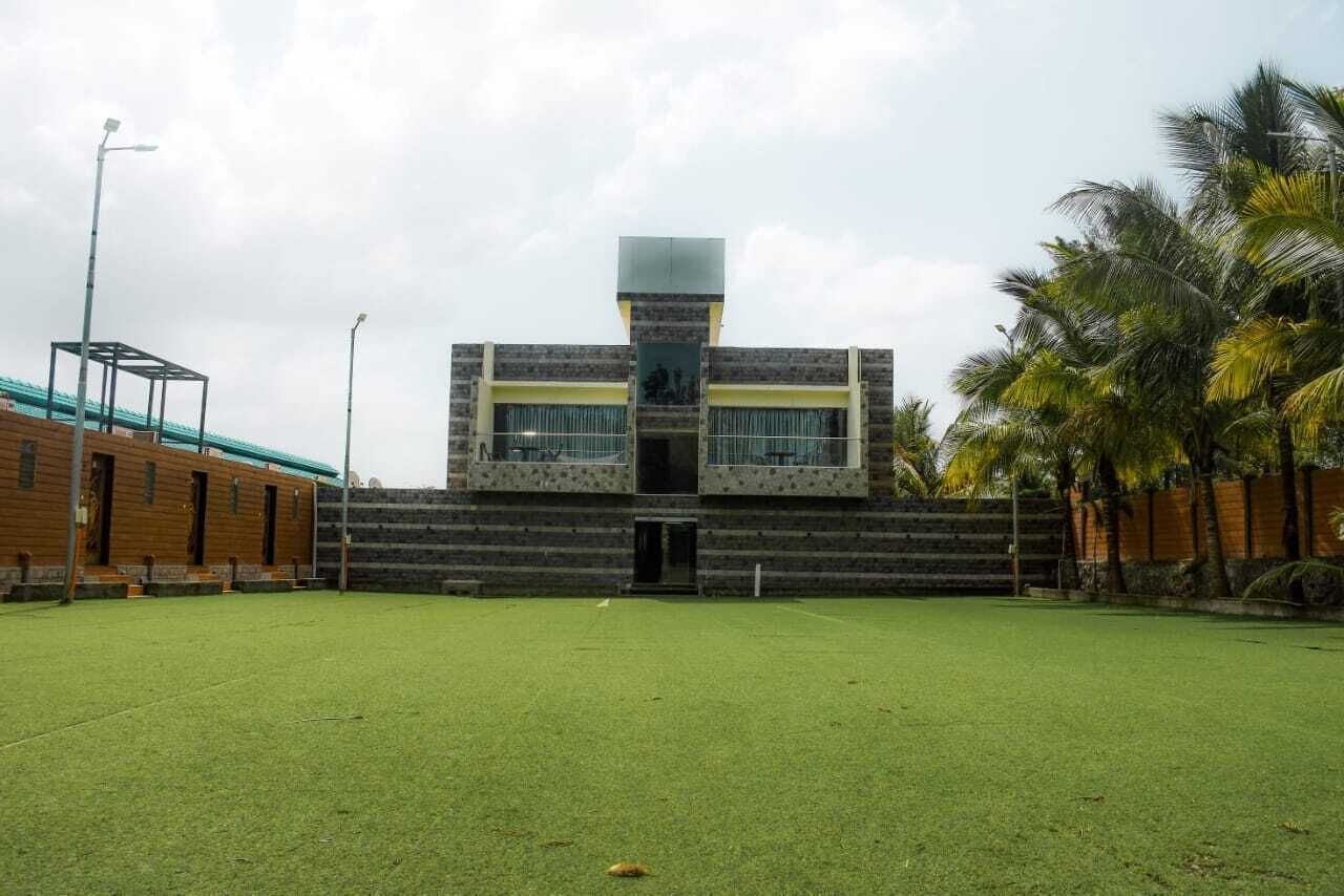 A modern building with a central tower, surrounded by a grassy area and palm trees.