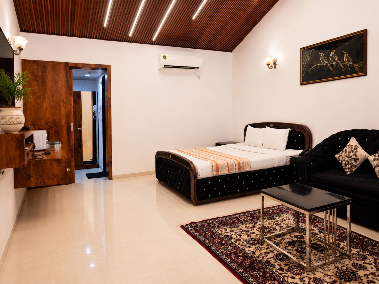 A modern bedroom with a bed, a sofa, a coffee table, and a patterned rug.