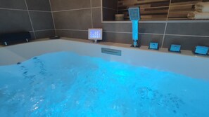 Una bañera con panel de control digital y cabezal de ducha de mano.