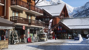 A wooden building with balconies, ski rental signs, and a sign for 'Vaujany'.